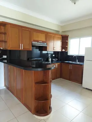 a kitchen with wooden cabinets and a black counter top at Espacioso apartamento en Puerto Plata in San Felipe de Puerto Plata