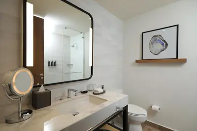 a bathroom with a sink and a mirror and a toilet at Courtyard by Marriott Santo Domingo Piantini in Santo Domingo