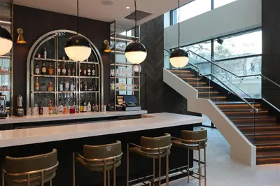 a bar with a staircase and a bar counter with stools at Courtyard by Marriott Santo Domingo Piantini in Santo Domingo