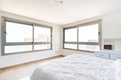 a white bedroom with large windows and a bed at 3 BDR Ocean View luxury Apartment . Sleeps 6 in Santo Domingo