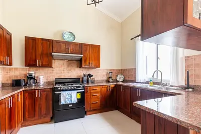 a kitchen with wooden cabinets and a black stove top oven at Novus Mare, Cabarete center! in Cabarete