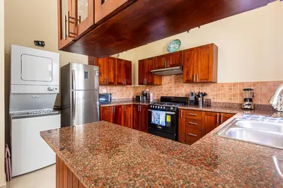 a kitchen with wooden cabinets and a granite counter top at Novus Mare, Cabarete center! in Cabarete