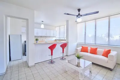 a living room with a white couch and red chairs at Rentamos Aparta Estudio for short or long stay in Santo Domingo