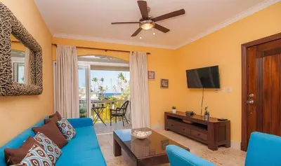 a living room with a blue couch and a tv at A pasos de la playa cerca de bares y restaurantes in Punta Cana