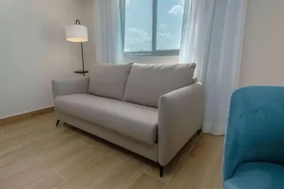 a couch in a living room with a lamp and a chair at Wyndham Garden El Morro Montecristi in El Rincón