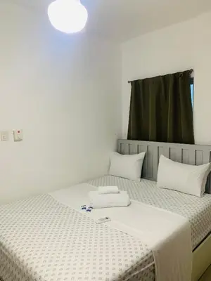 a bedroom with a bed with white sheets and a window at Plataview Apartahotel 3B in Monte Plata
