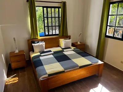 a bedroom with a bed with a checkered blanket on it at Villa unter Palmen in Jarabacoa