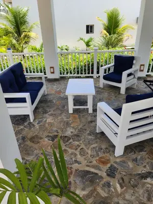 a patio with chairs and a table and palm trees at Bella Villa room with large pool and close to beach in Las Galeras
