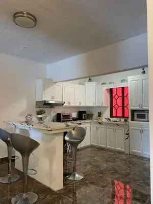 a kitchen with white cabinets and bar stools at Casa Jacaranda -10 pax, Cerca de la Playa in Las Galeras