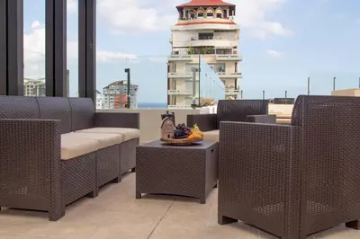 a balcony with wicker chairs and a lighthouse in the background at Brand New Luxury Home in Santo Domingo