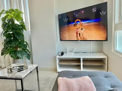 a living room with a blue couch and a flat screen tv at Cozy City Center Condo Full AC in Santo Domingo