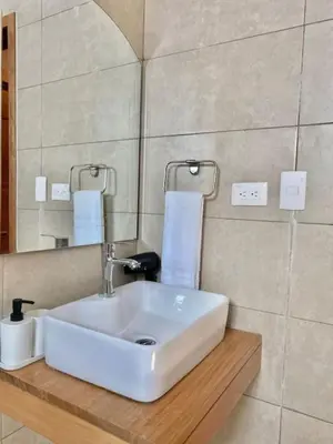 a bathroom with a white sink and a mirror at Stylish Apt Full AC King Bed in Los Prados