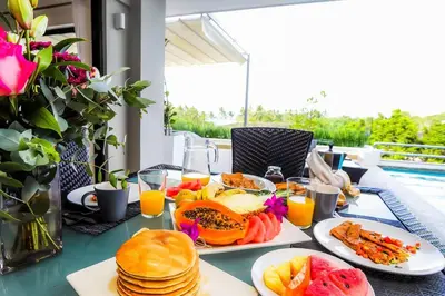 a table with plates of food and pancakes and orange juice at RIBERAMAR Las Terrenas, Samana in Las Terrenas