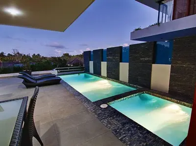 a patio with two swimming pools with chairs and lights at RIBERAMAR Las Terrenas, Samana in Las Terrenas