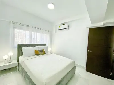 a white bedroom with a bed and a window at Lovely City Center Condo in Los Prados