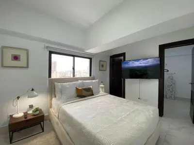 a bedroom with a large white bed and a television at Lovely City Center Condo in Los Prados