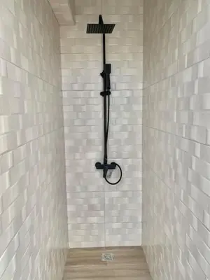a shower in a bathroom with white tile walls at Lovely City Center Condo in Los Prados