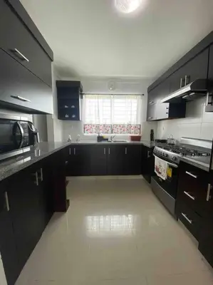 a kitchen with black cabinets and a white floor at Hermoso conjunto residencial con piscina in Santiago de los Caballeros