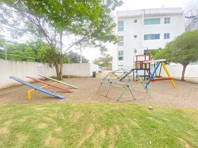 a playground with colorful swings in a yard at Hermoso conjunto residencial con piscina in Santiago de los Caballeros