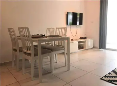 a dining room table with four chairs and a television at Estrella Dominicus con hermosa piscina! 1st floor in La Laguna