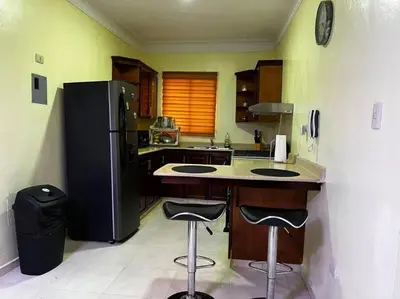 a kitchen with a black refrigerator and two bar stools at Entire apartment Tu Nido De Amor 2 Santo Domingo West in Santo Domingo