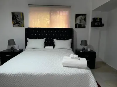 a bedroom with a large bed with white sheets and two lamps at Entire apartment Tu Nido De Amor 2 Santo Domingo West in Santo Domingo