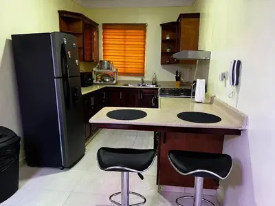 a kitchen with a black refrigerator and two bar stools at Entire apartment Tu Nido De Amor 2 Santo Domingo West in Santo Domingo