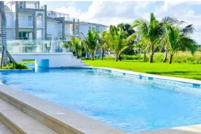 a swimming pool in front of a house with palm trees at Hard Rock at Cana Pearl 1 by Unwind Properties in Punta Cana