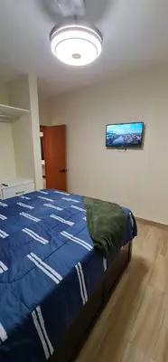 a bedroom with a bed with a blue comforter at Apartament central frente al mar in San Felipe de Puerto Plata