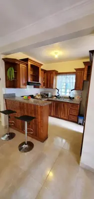 a kitchen with wooden cabinets and bar stools at Pine Tree Entire House 2B Gated Com in Higuey