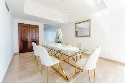 a dining room with a glass table and white chairs at Habitación Privada con vista al mar Ámbar, Malecon Santo Domingo in Santo Domingo