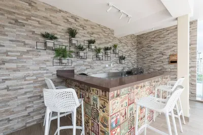 a kitchen with white chairs and a stone wall at Stunning infinity pool apartment in Santo Domingo