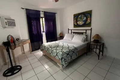 a bedroom with a bed and a desk and window at Caribe Campo Sosua in Sosúa