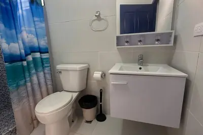 a white bathroom with a toilet and a sink at Caribe Campo Sosua in Sosúa