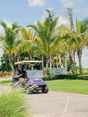 a man riding a purple golf cart at Hard Rock Getaway • 2BR with Golf + Pool Views in Punta Cana