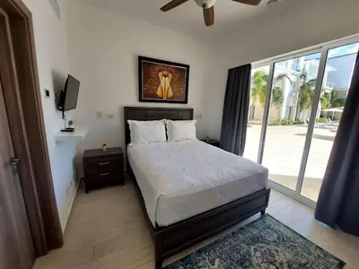 a bedroom with a bed and a large window at Hard Rock Getaway • 2BR with Golf + Pool Views in Punta Cana