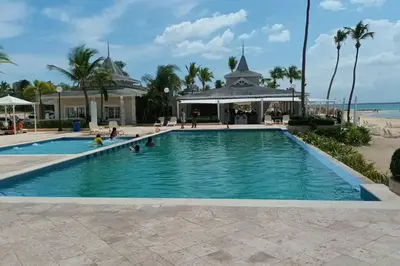 a pool at the beach with people in the water at Confortable apartamento en Playa Nueva Romana in San Pedro de Macorís