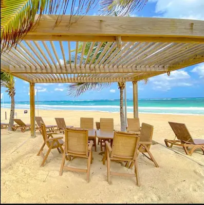 a table and chairs on a beach with the ocean at Hard Rock at Cana Rock 3 by Unwind Properties in Punta Cana