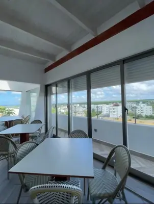 a white table and chairs in a room with windows at All Seasons Hotel in Bayahibe