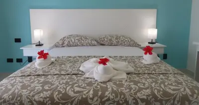 a bed with white towels and red flowers on it at All Seasons Hotel in Bayahibe