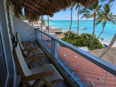 two chairs sitting on a balcony overlooking the ocean at Dios es Fiel - Ali Hotel in Punta Cana