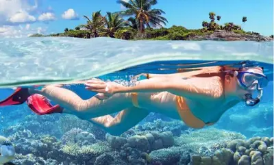 a woman swimming in the water near a reef at Dios es Fiel - Ali Hotel in Punta Cana