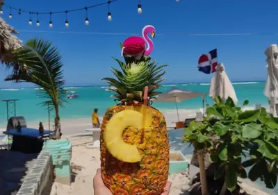 a person holding a pineapple cut in half with a drink at Dios es Fiel - Ali Hotel in Punta Cana