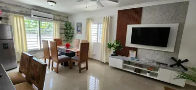 a living room with a table and a television on a wall at Rooftop with Pool, La Romana, Villa Doña Julia, At Paula Isabel in La Romana