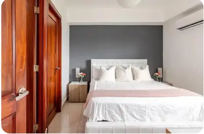 a bedroom with a white bed and a gray wall at Condo Apartment in Ciudad Nueva