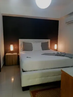 a bedroom with a large white bed with a black wall at Condo Apartment in Ciudad Nueva