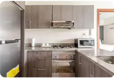a kitchen with wooden cabinets and a stove top oven at Condo Apartment in Ciudad Nueva