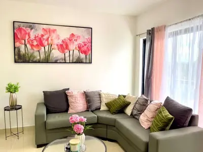 a living room with a couch and a painting of pink flowers at Torre Solarium next to PUCMM in Santiago de los Caballeros
