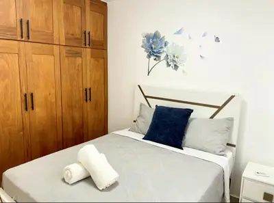 a bedroom with a bed with blue and white pillows at Torre Solarium next to PUCMM in Santiago de los Caballeros