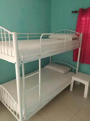 two bunk beds in a room with a chair at Central Rooms Bayahibe in Bayahibe